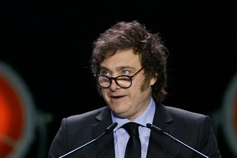 a man in a suit and tie speaking into microphones